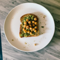 A picture of avocado chickpea toast on a plate sitting on a kitchen counter