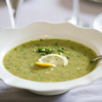 green soup (spinach, celery, parsley, lemon) in a bowl on a table set for dinner