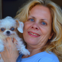 50 year old women with  long strawberry  blonde hair, blue eyes ,no wrinkles , no makeup with her  small white dog that  both  her and the dog are smiling