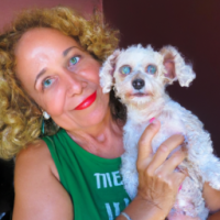 50 year old women with  long strawberry  blonde semi curly  hair, blue eyes ,no wrinkles , no makeup with her  small white dog with her smiling