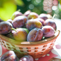 fresh plums in basket on table outside
